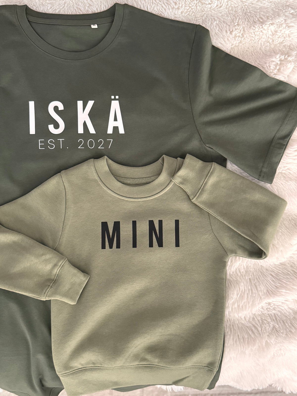 Army green t-paita valkoisella ISKÄ-painatuksella ja vuosiluvulla.