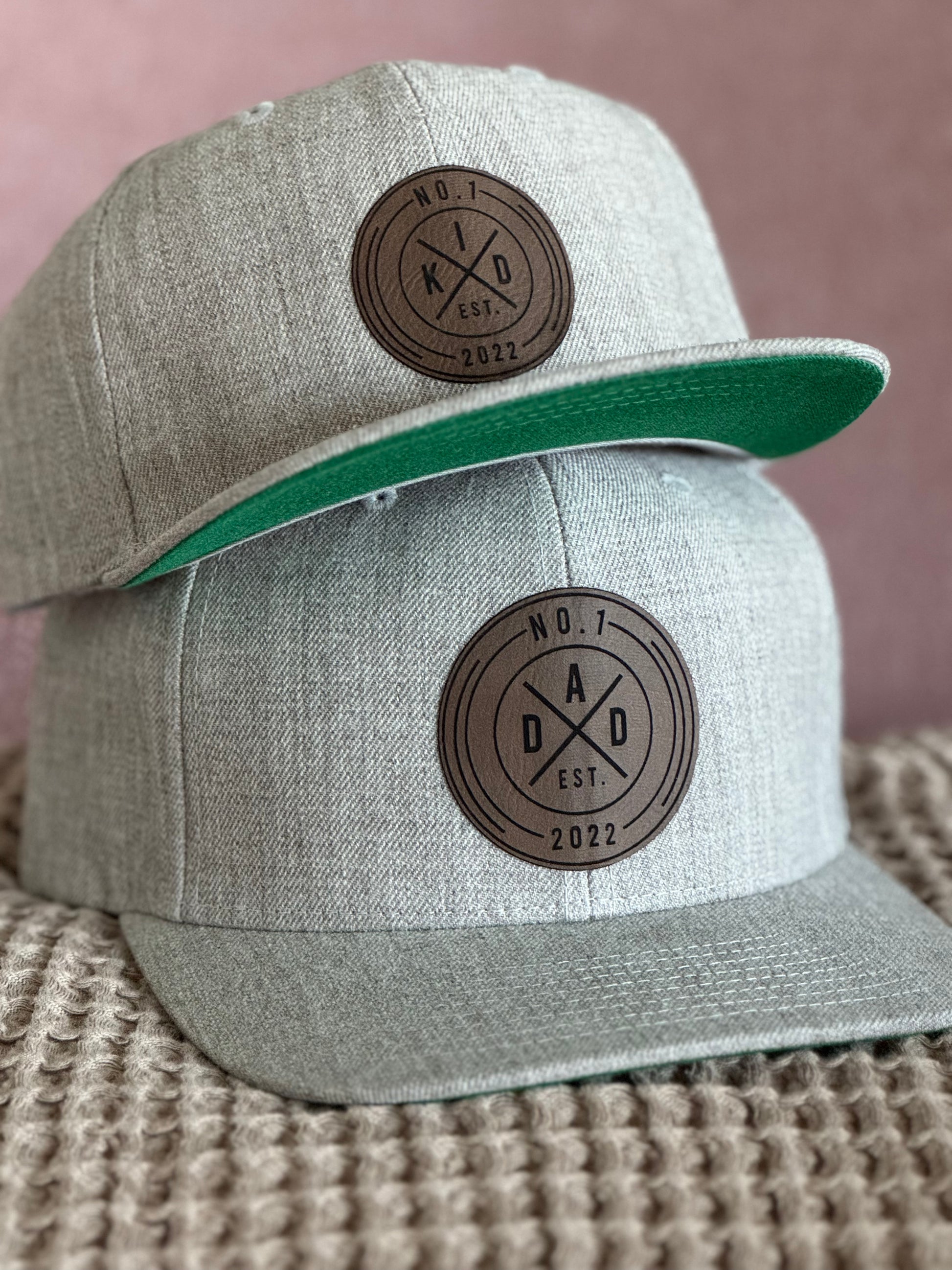 Harmaa lasten snapback-lippalakki ruskealla pyöreällä nahkajäljitelmämerkillä.