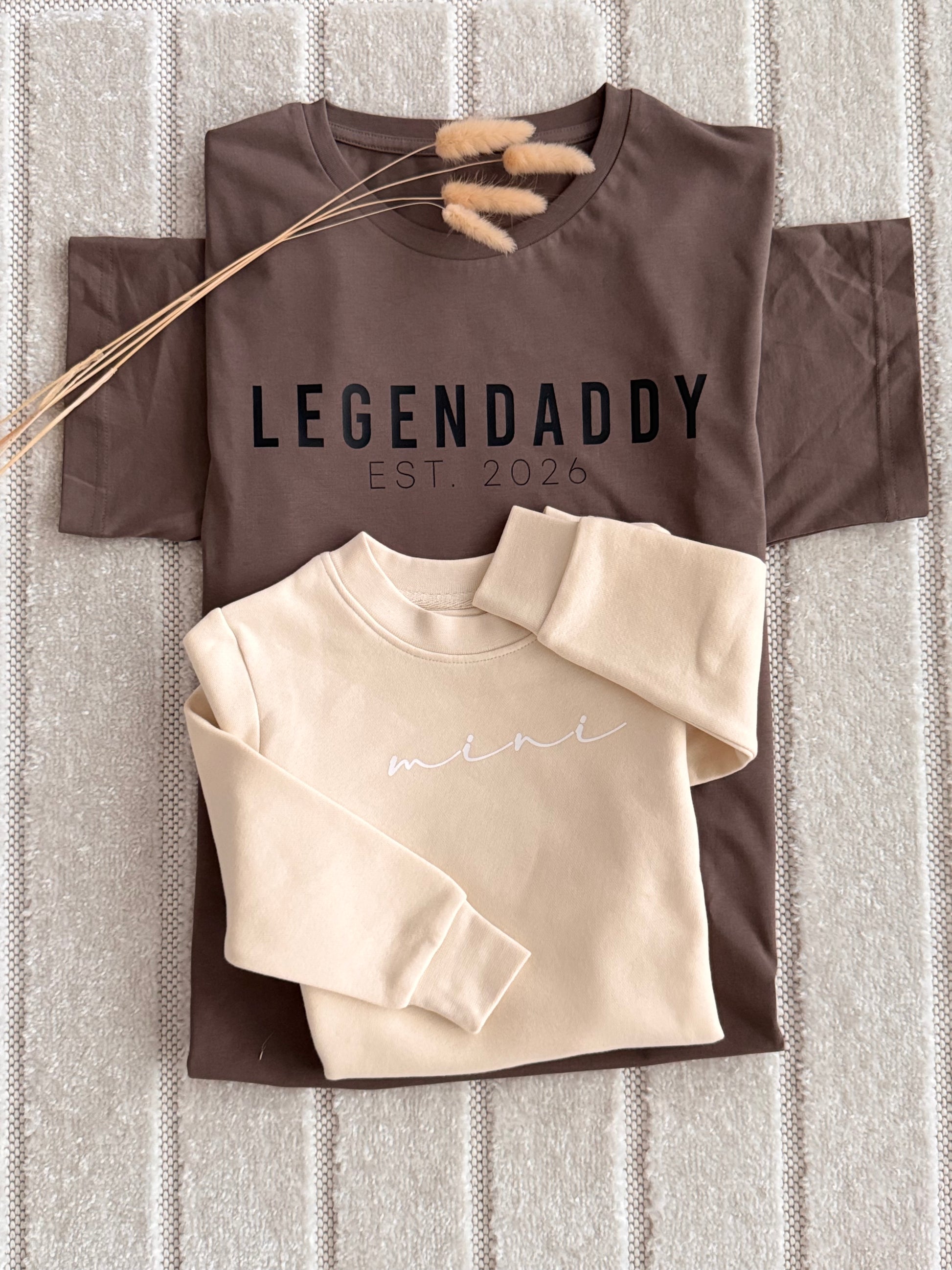 A styled flat-lay of two sweatshirts on a textured gray knit blanket.