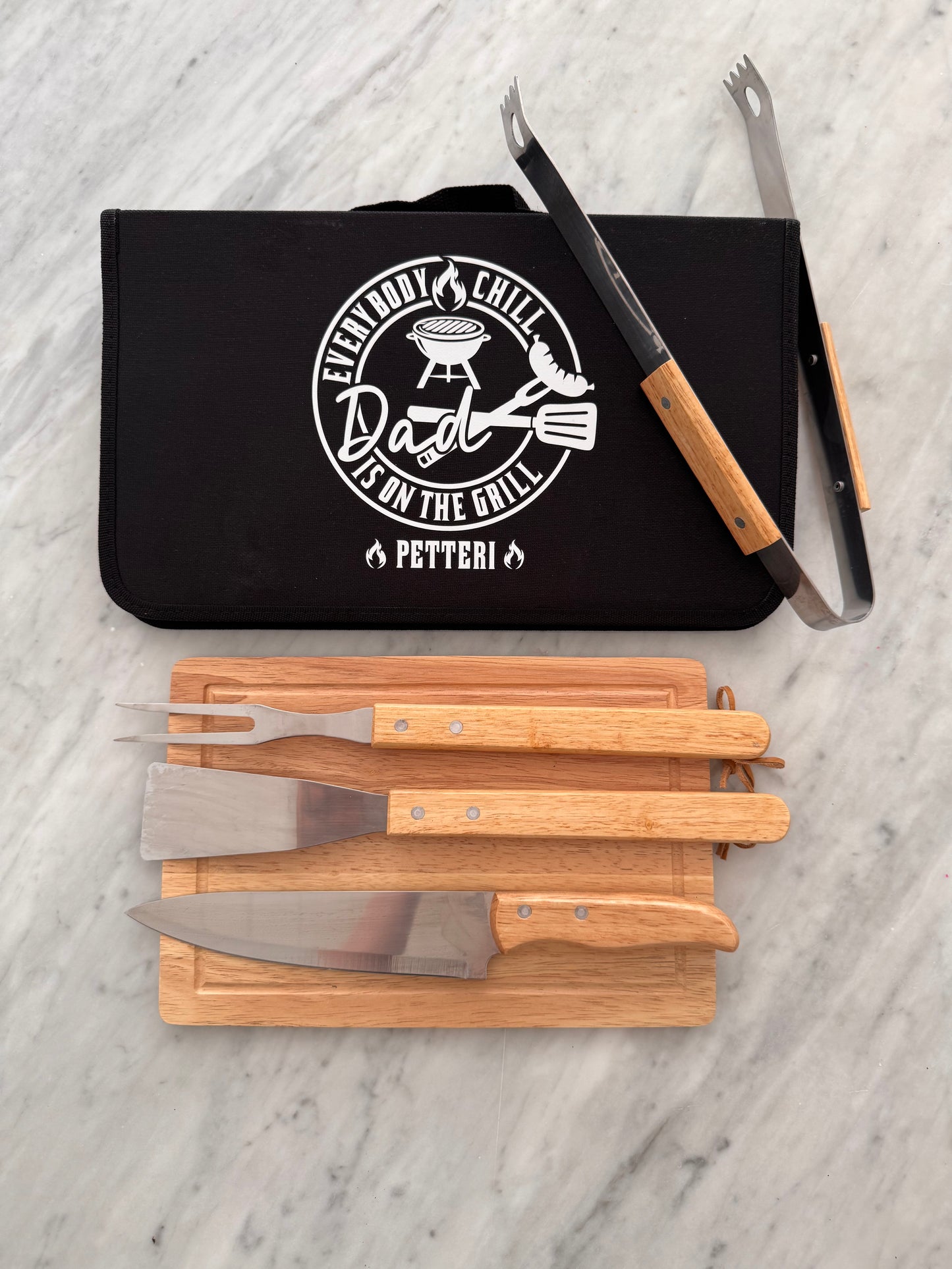 Black BBQ tool set with wooden handles on a light gray surface