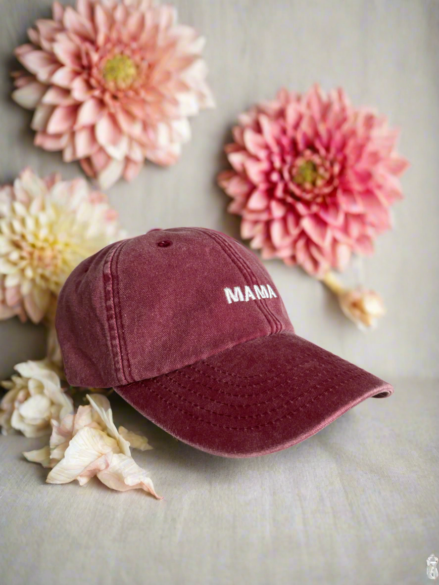 red cap with 'MAMA' text on a surface with pink and white flowers.